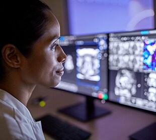 Clinician facing multiple monitors showing MR scans