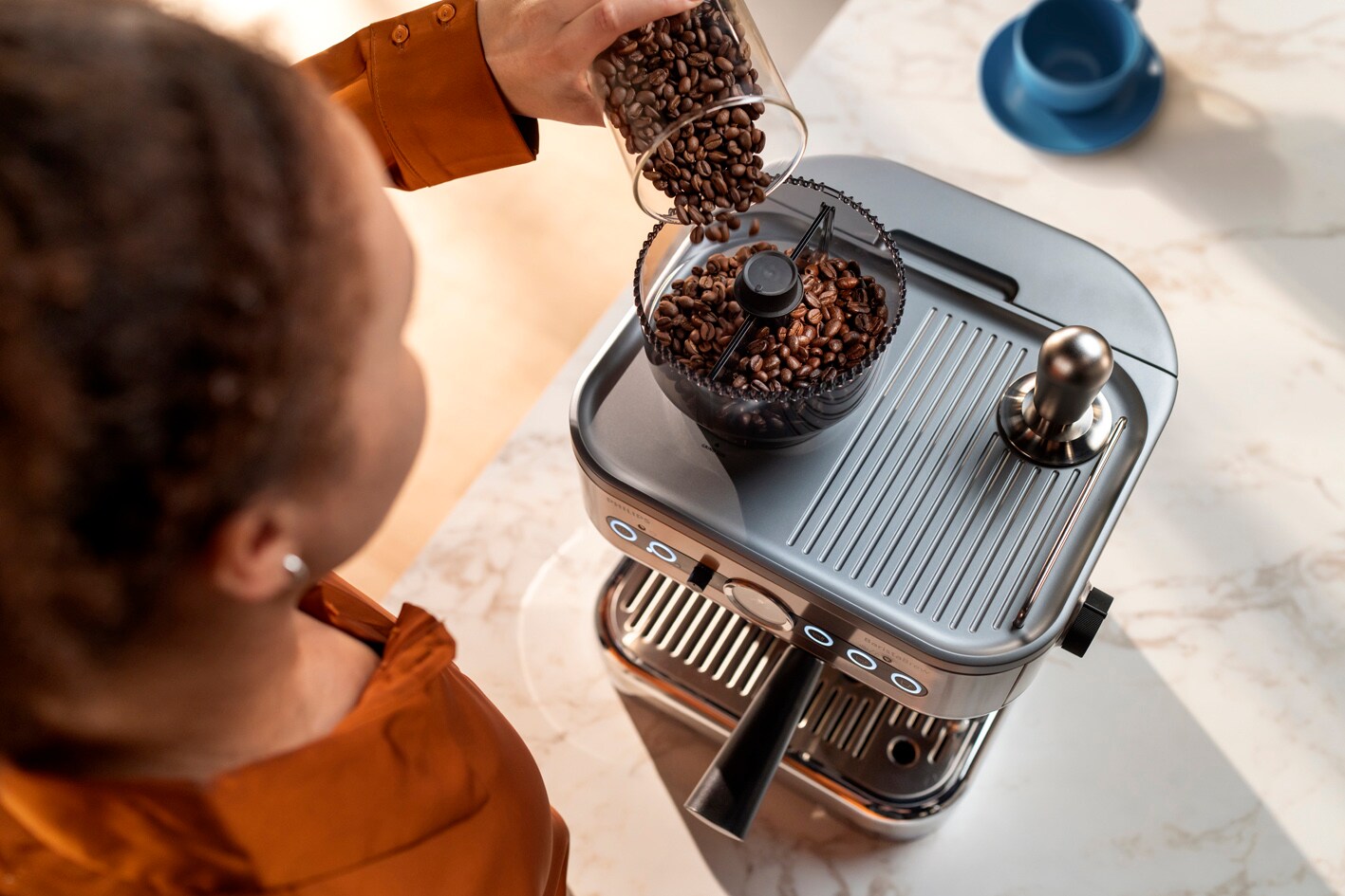 A young lady is pouring coffee bean into the Philips Barista brew coffee bean container